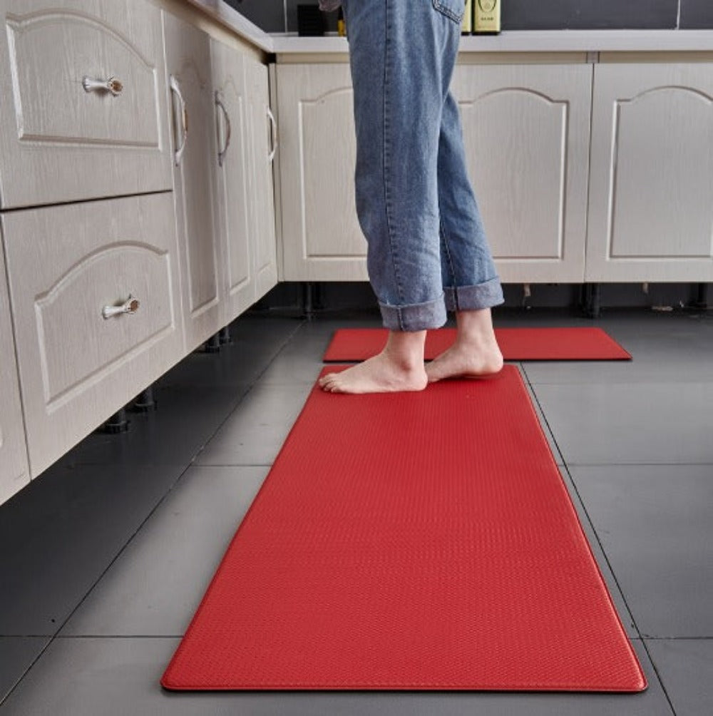 Person standing on a red mat in a kitchen