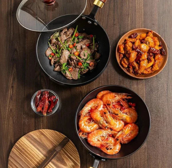 Assorted dishes including shrimp, stir-fried vegetables, and a bowl of fried food on a wooden table.