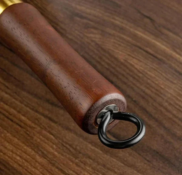 Close-up of a wooden handle with a metal ring on a wooden surface