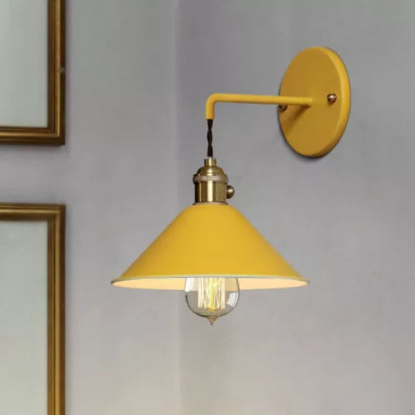 Yellow wall lamp with a gold fixture on a gray wall.
