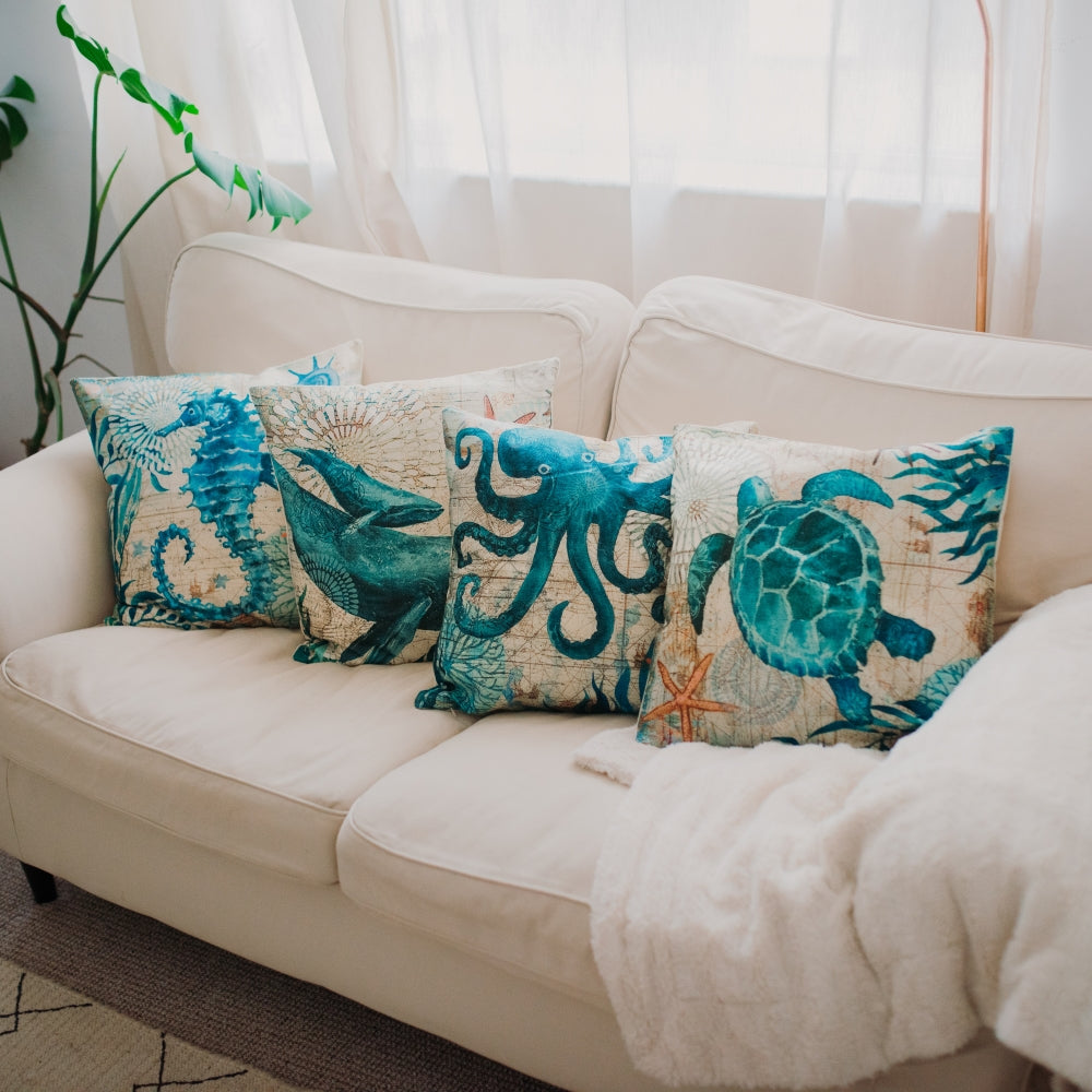 Decorative pillows with ocean-themed designs on a beige sofa.