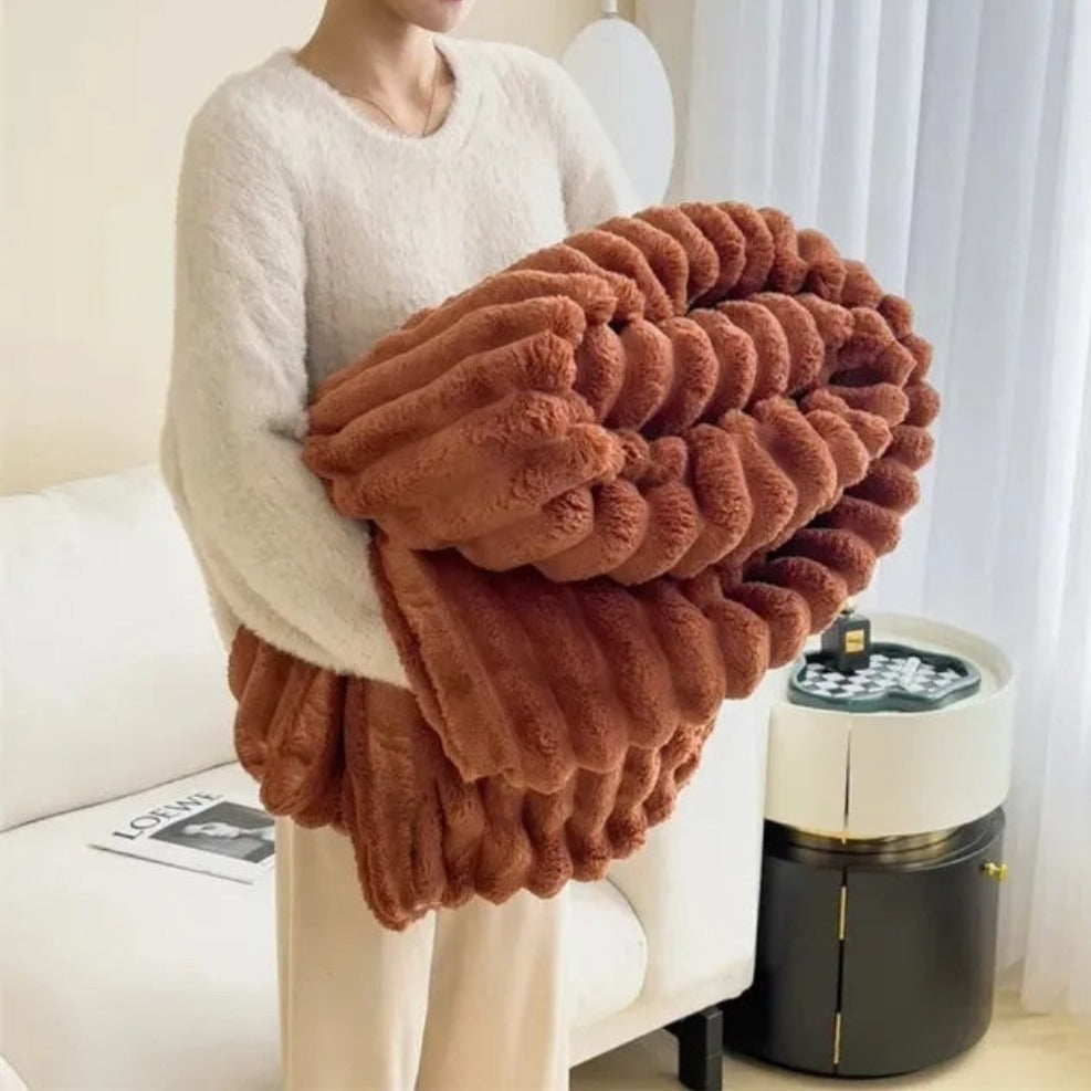 Person holding a large brown fluffy blanket in a living room setting.
