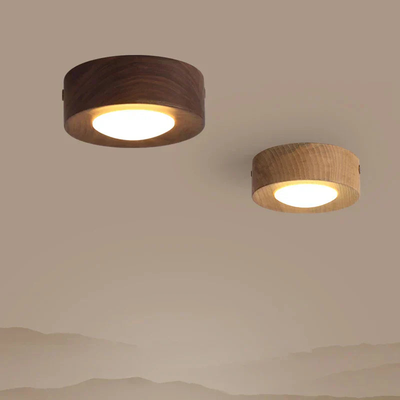Two round ceiling lights with wooden finishes on a beige wall.