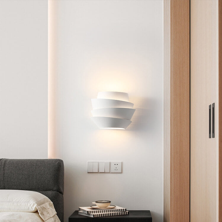 Modern wall sconce on a white wall with a wooden door to the right