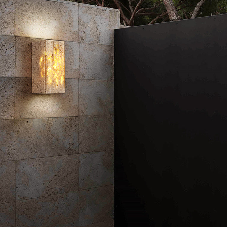 Square wall light fixture on a stone wall with a dark background