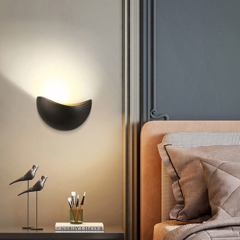 Modern wall lamp on a wall next to a bed with decorative items.