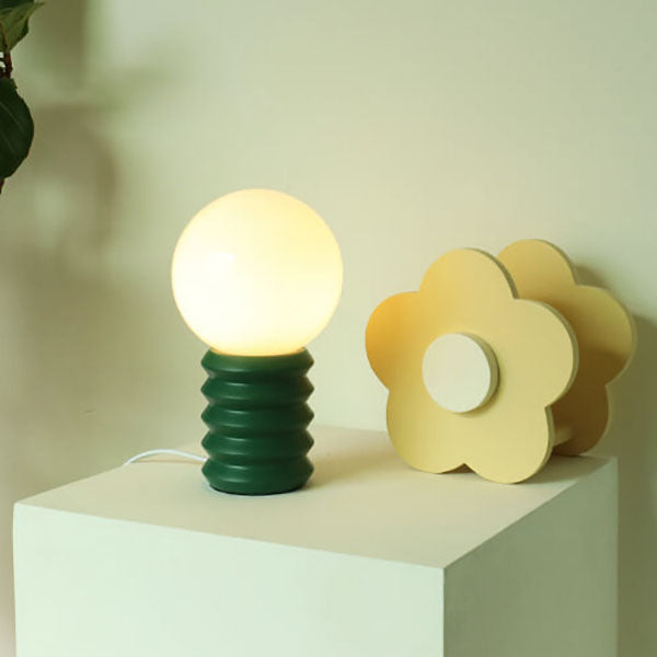 Decorative table lamp with a flower design on a white surface against a light green background
