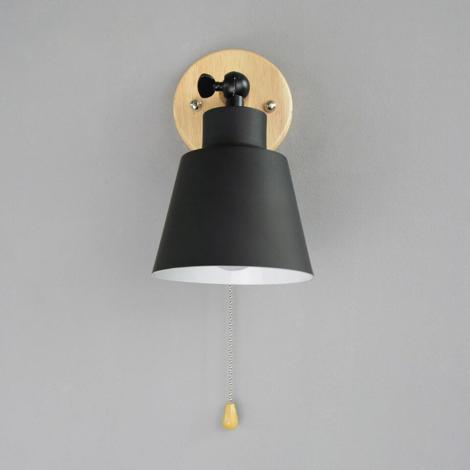 Wall-mounted lamp with black shade and gold pull switch on a gray background