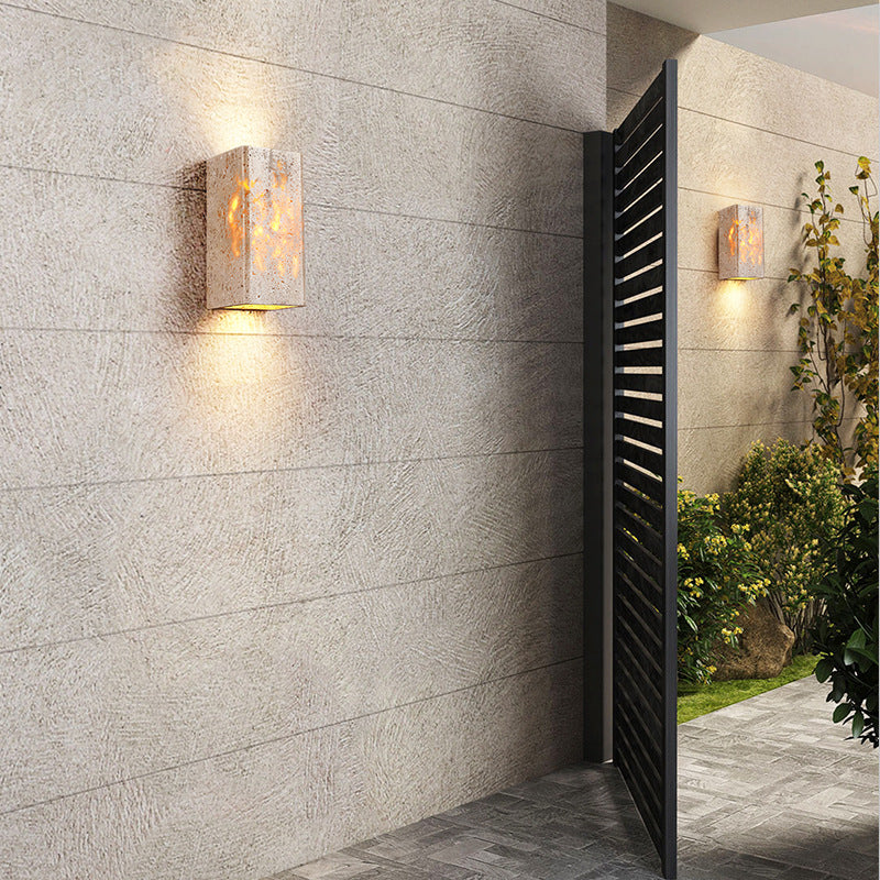 Modern outdoor setting with textured wall, glass sconces, and a black gate.