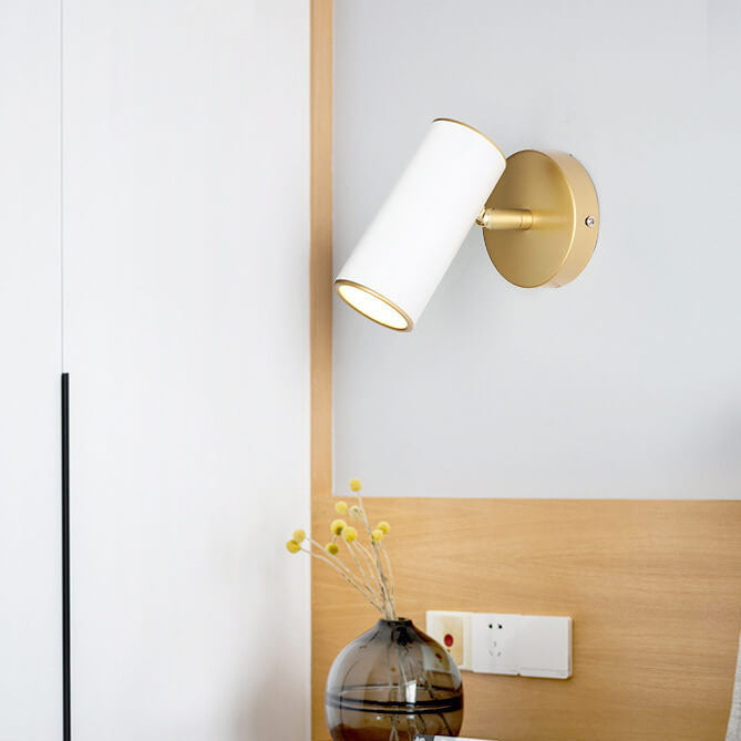 Modern wall lamp with white shade and gold fixture on a white wall.