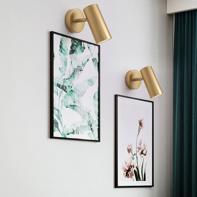 Gold wall sconces with framed artwork on a light gray wall.