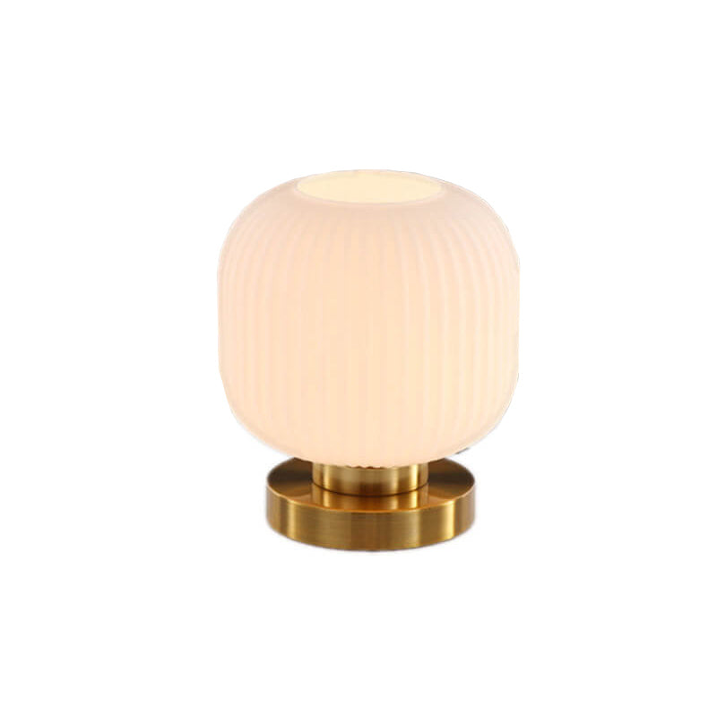 Table lamp with a ribbed white shade and gold base on a white background
