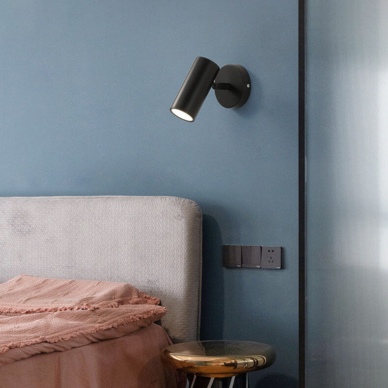 Black wall-mounted light fixture on a blue wall above a bed with pink bedding.