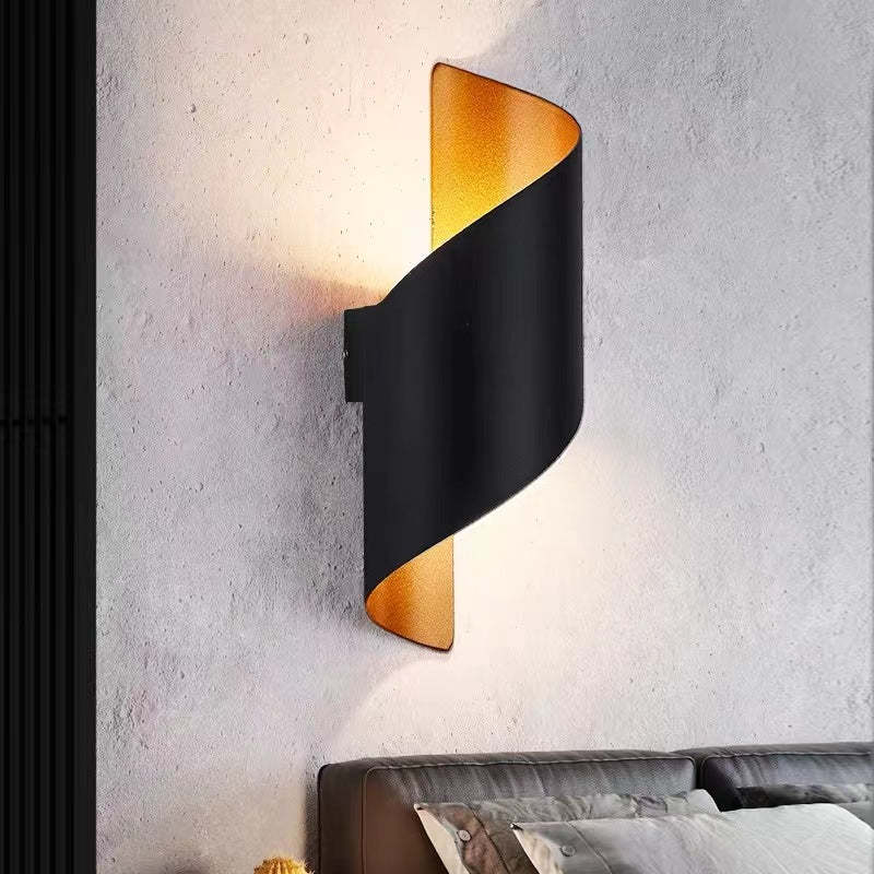 Modern wall lamp with black and gold design on a textured wall.