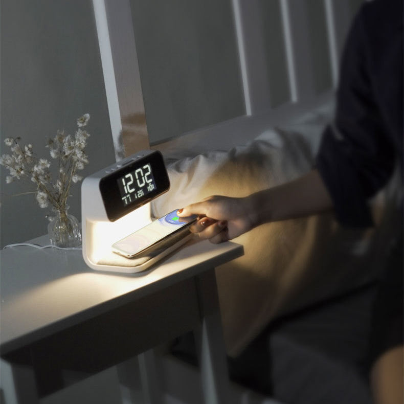 Smart night light with digital display on a bedside table, person using phone.