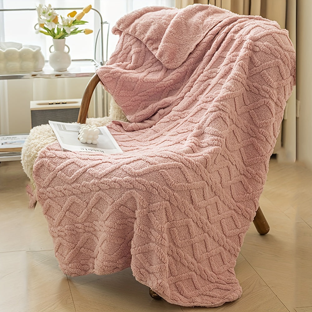 Pink textured blanket draped over a chair in a room with a vase of flowers on a table.