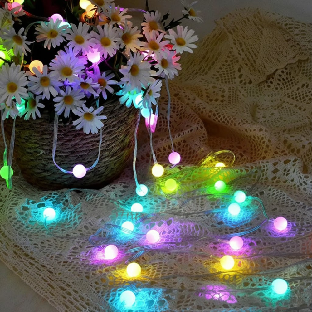 String lights with colorful bulbs on a lace tablecloth with flowers in the background