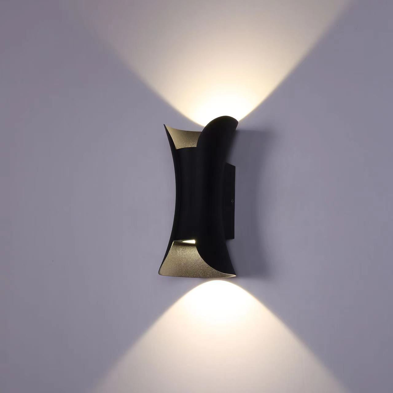 Modern wall lamp with black and gold design on a gray wall