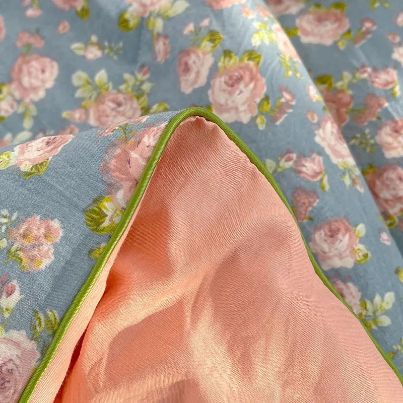 Floral fabric with pink flowers on a blue background and a peach-colored fabric underneath.