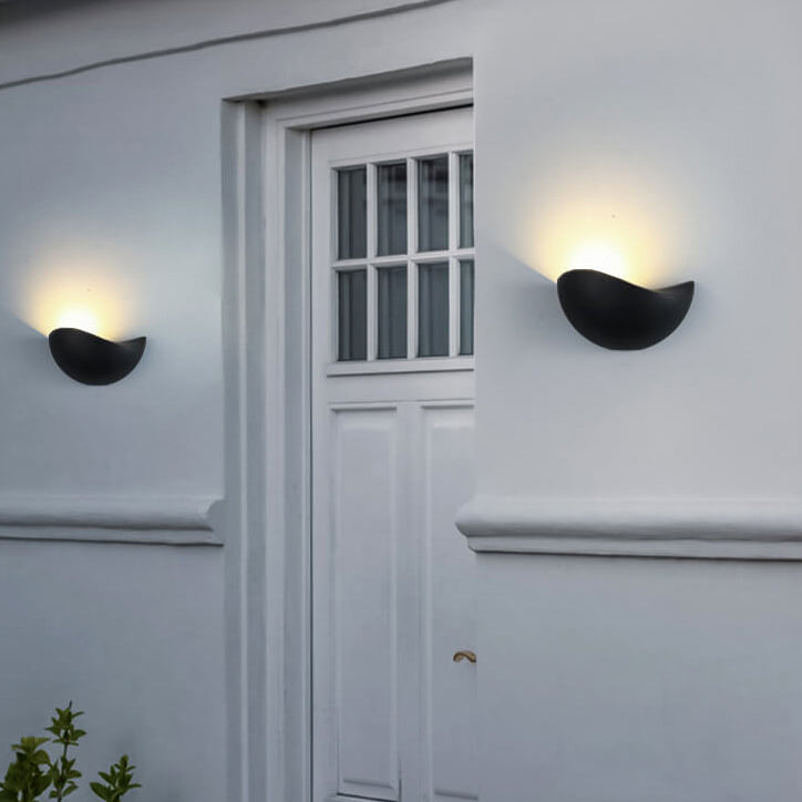 Black wall-mounted outdoor lights on a white building facade.