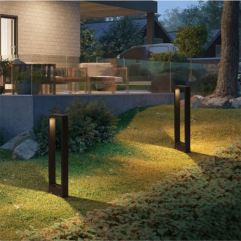 Garden with outdoor lighting fixtures casting a warm glow on grass and plants.