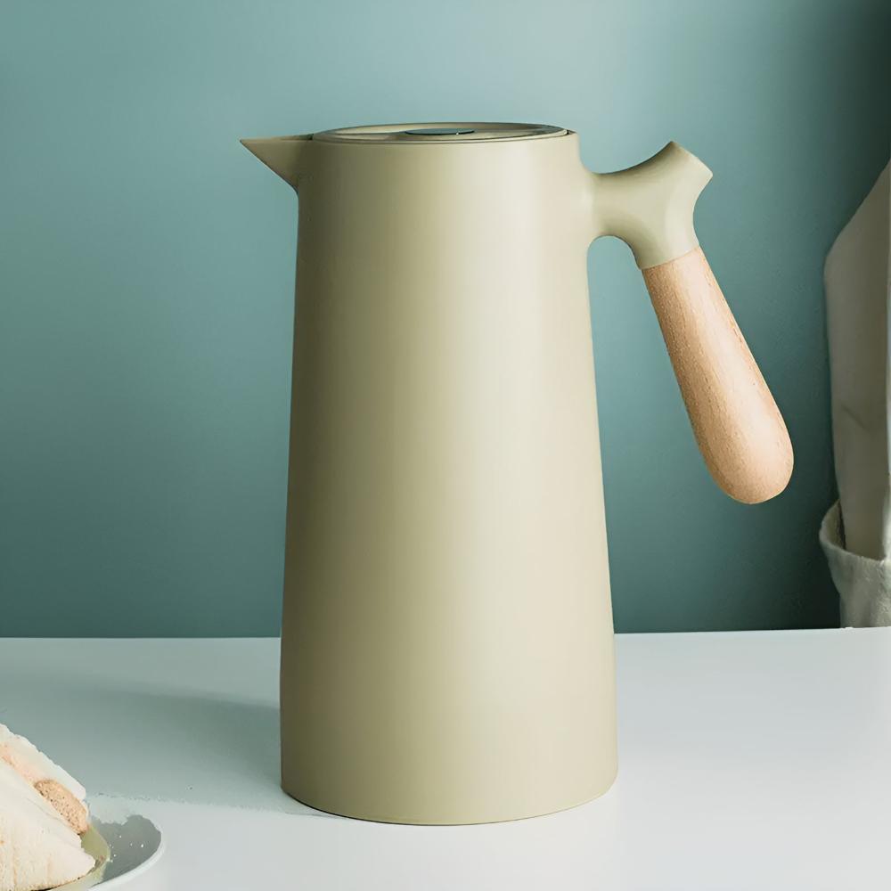 Beige ceramic pitcher with wooden handle on a light gray surface against a teal background