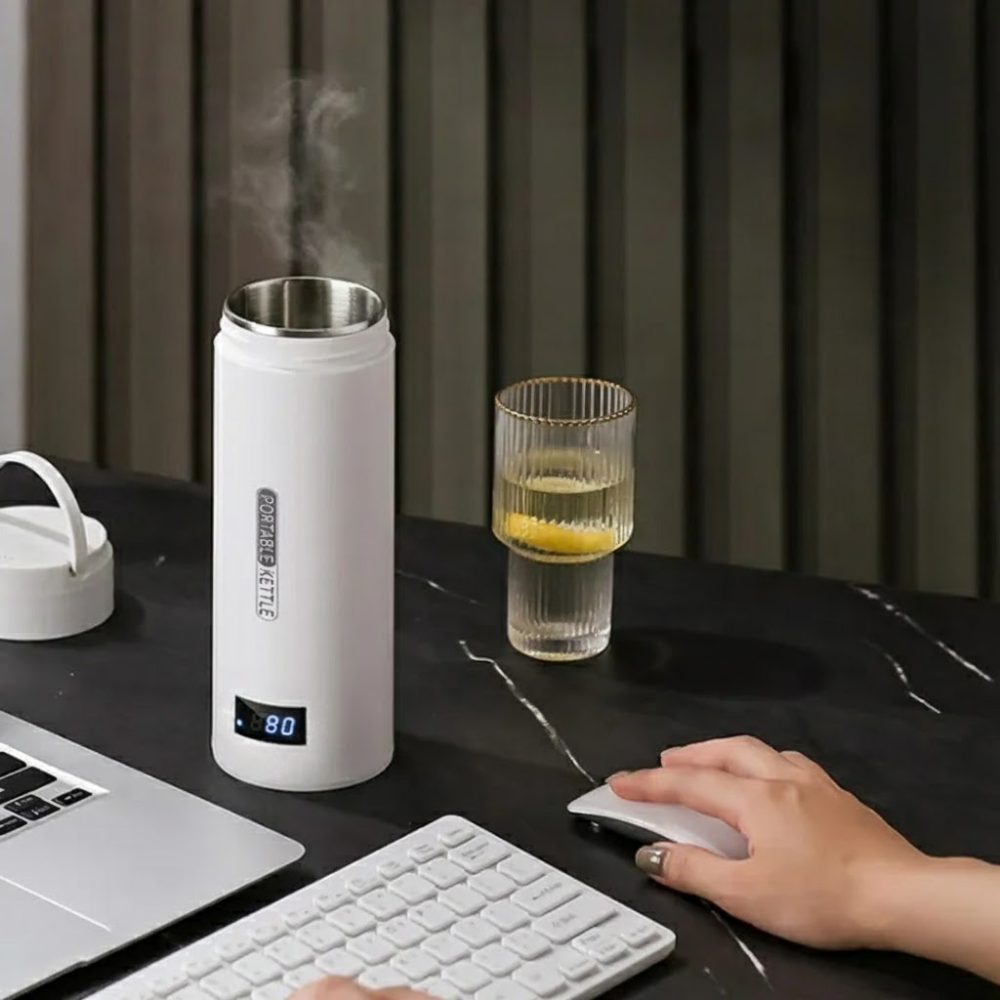 White electric kettle with digital display on a desk next to a glass of water and a laptop.