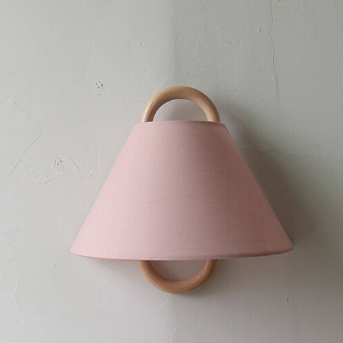 Pink wall light fixture with wooden accents on a gray wall