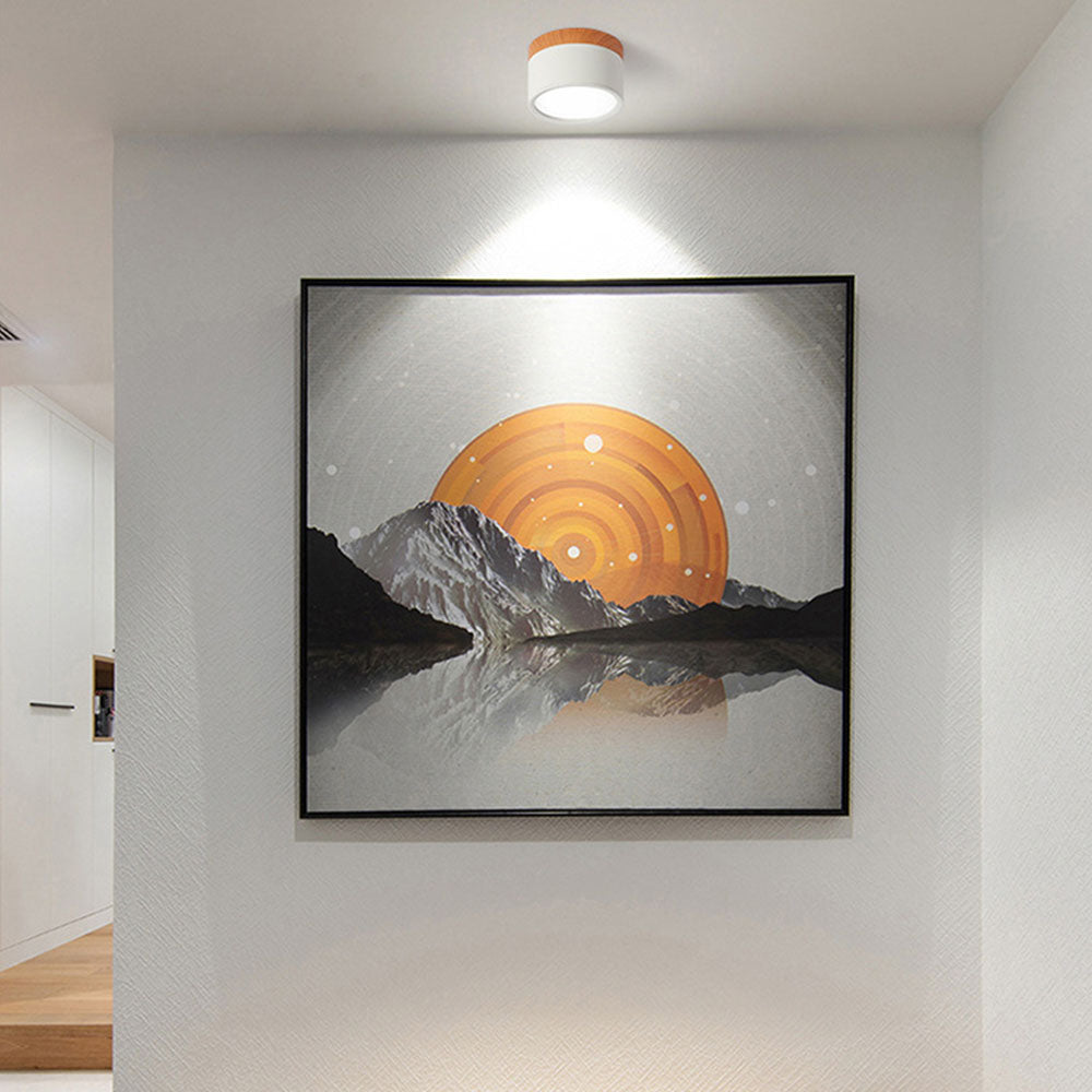 Framed artwork of a mountain landscape with an orange sun on a wall in a room.