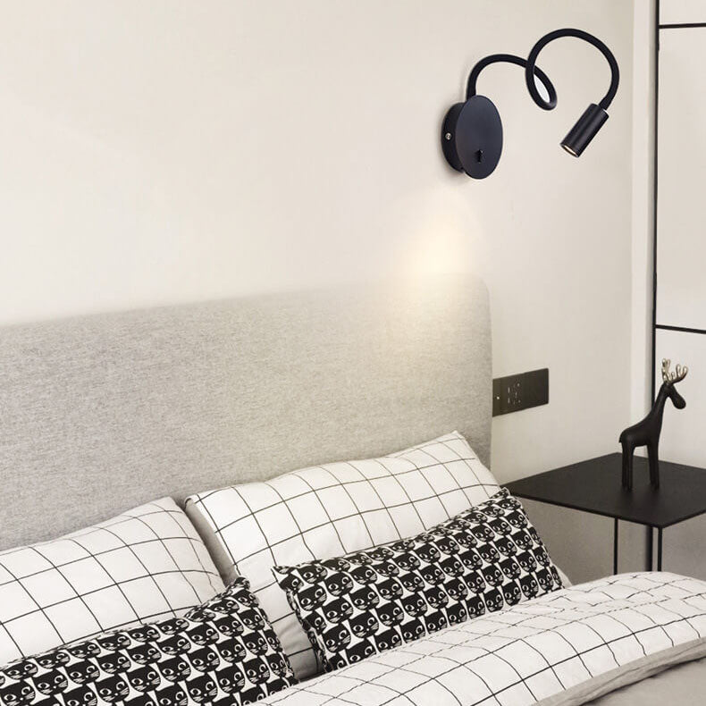Bedroom interior with black wall lamp, bed with patterned pillows, and side table.