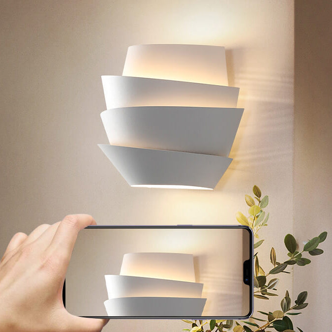 Modern wall light fixture with a hand holding a phone taking a photo.