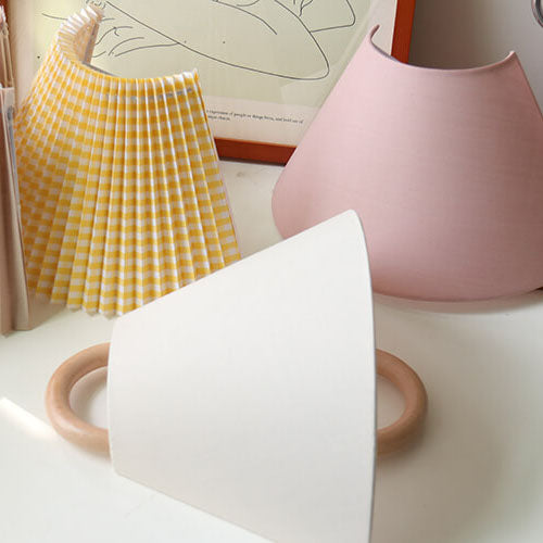 Three ceramic vases in different colors on a white surface with a yellow checkered object in the background.