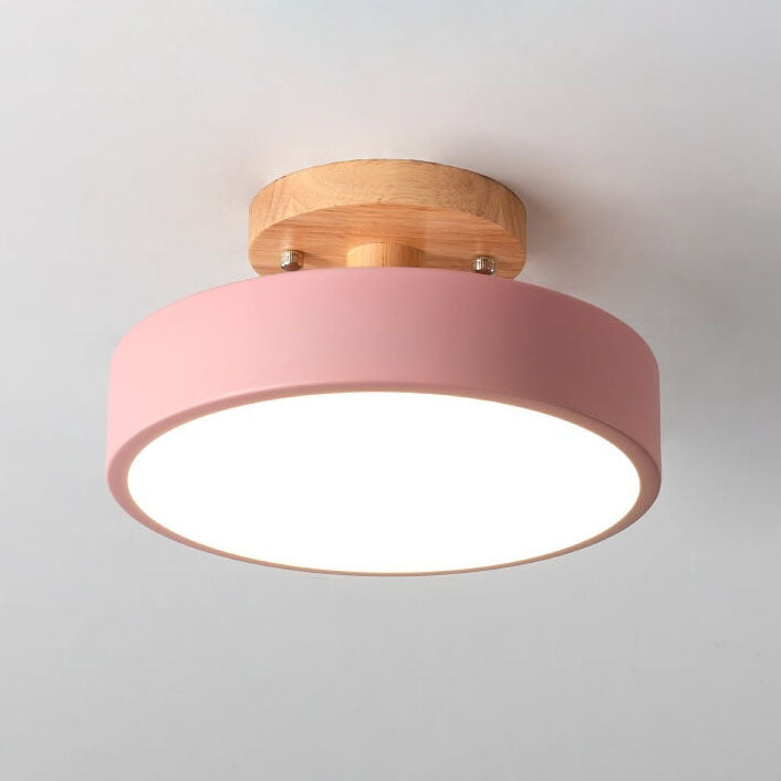 Ceiling light fixture with pink shade and wooden fixture on a gray background