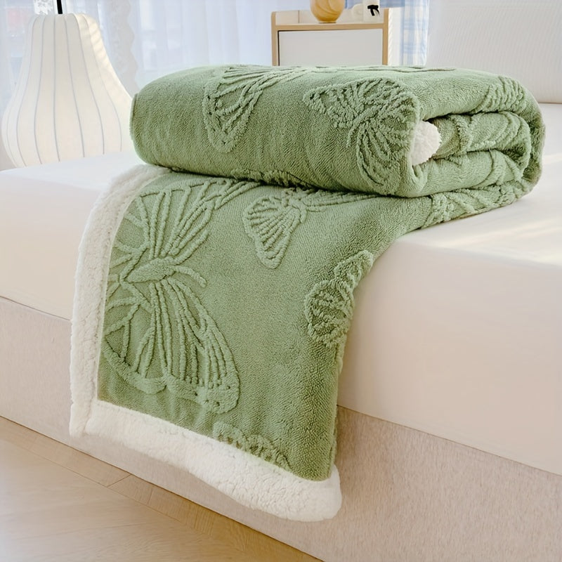 Green textured blanket with butterfly patterns on a white surface
