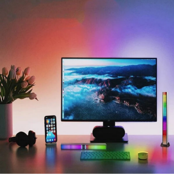 Modern office setup with a computer monitor, keyboard, smartphone, and colorful LED lights on a desk.