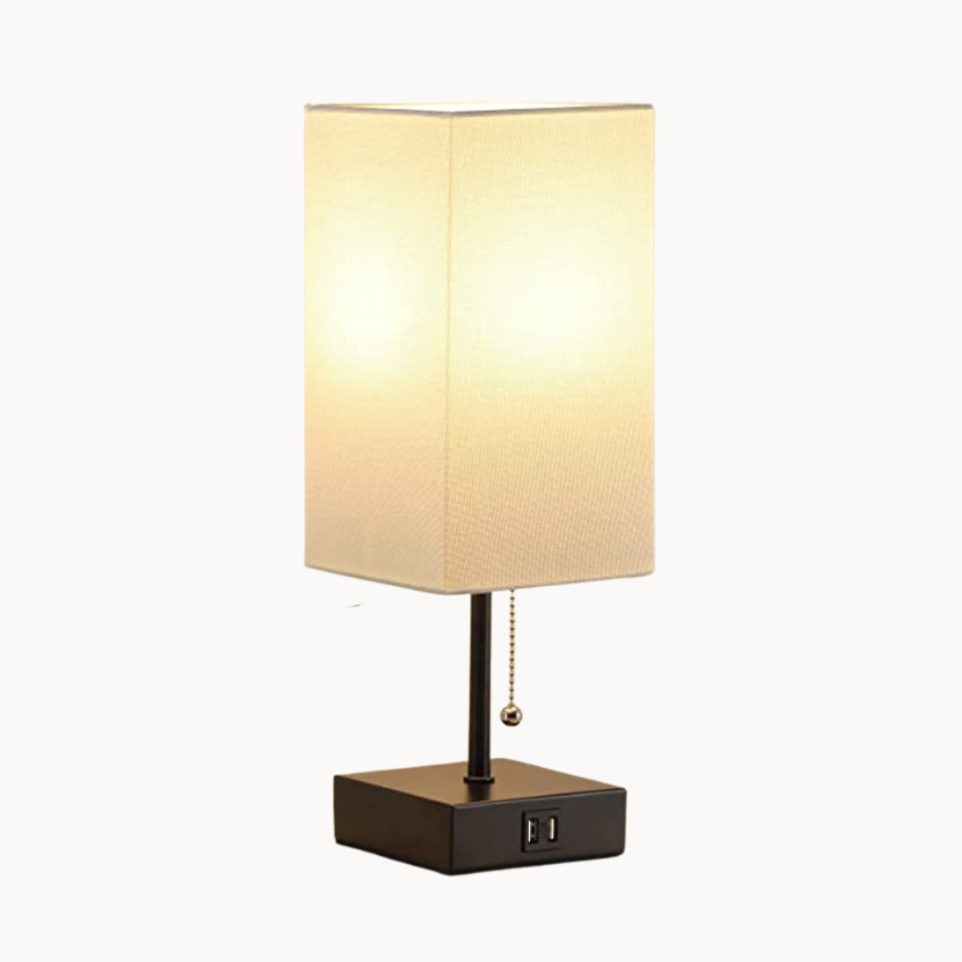 Table lamp with beige shade and black base on a white background