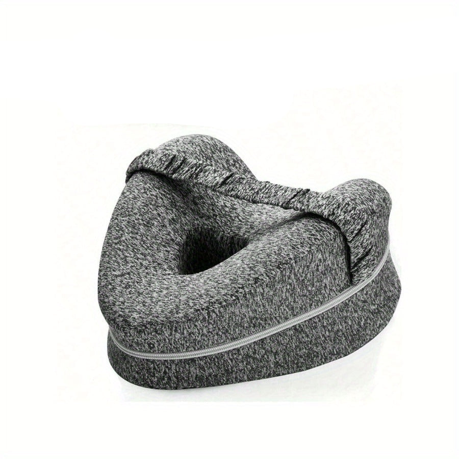 Gray inflatable travel pillow with a woman lying on a bed in the background