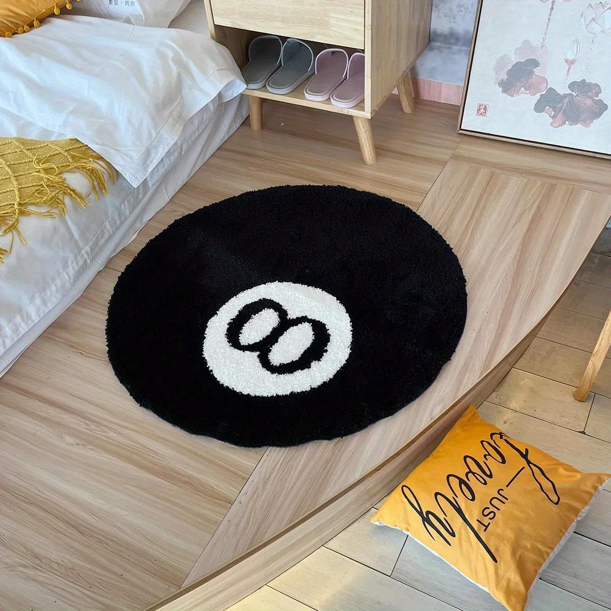 Round black rug with a white circle design on a wooden floor in a bedroom.