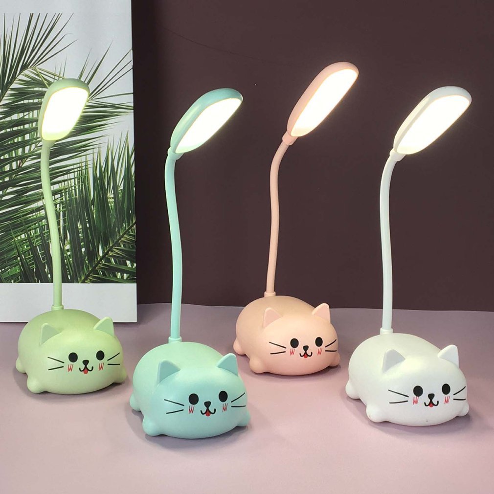 Set of four cat-shaped desk lamps in different colors on a pink surface.