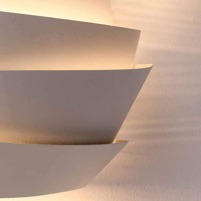 Modern wall light fixture casting shadows on a textured wall.