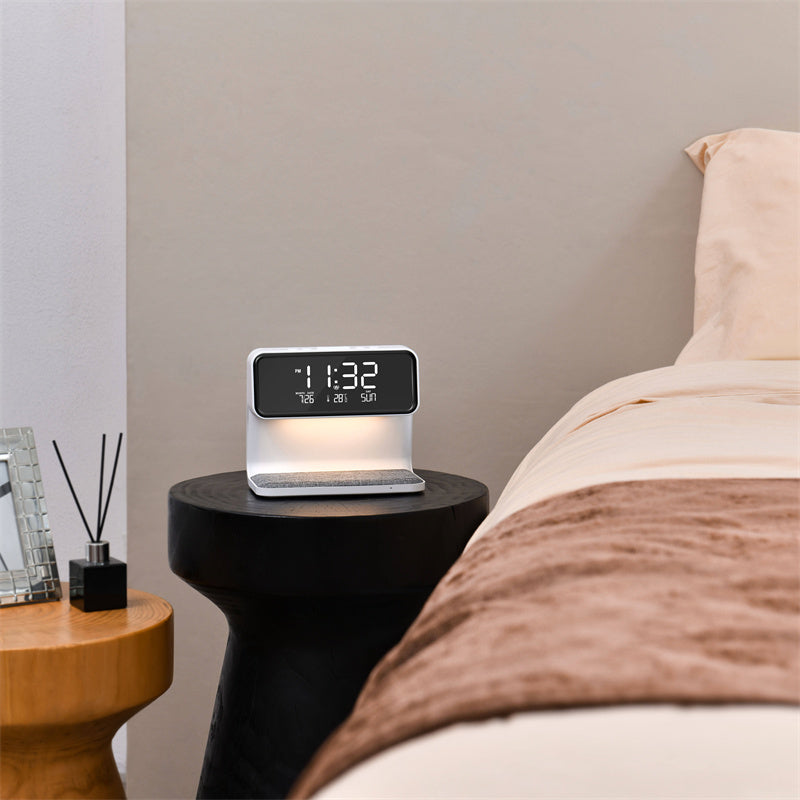 Digital clock on a nightstand next to a bed