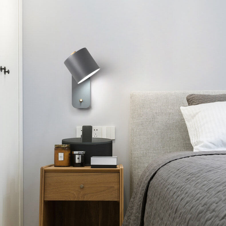 Bedroom with wooden nightstand, wall lamp, and bed with gray bedding.