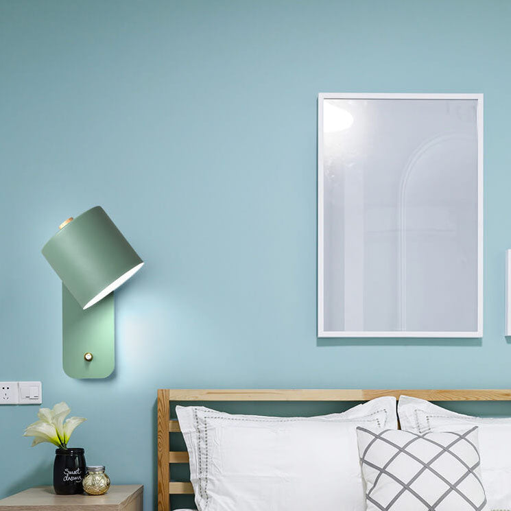 Bedroom interior with a light blue wall, green wall lamp, and framed mirror.