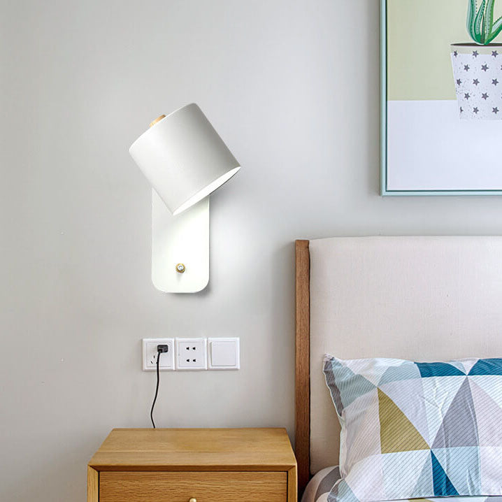 Bedroom with a wall-mounted lamp, nightstand, and bed with a geometric pillow.