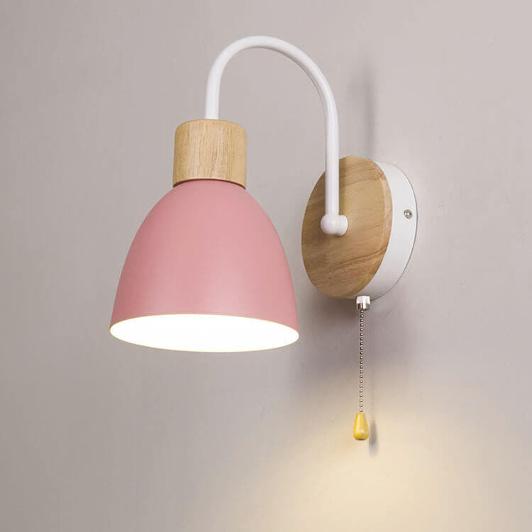 Wall lamp with pink shade and wooden fixture on a gray wall