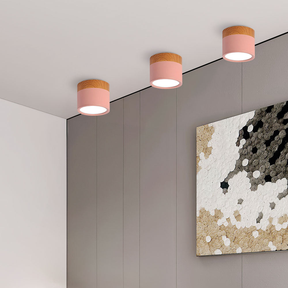 Three pink ceiling lights on a gray wall with abstract art in the corner.