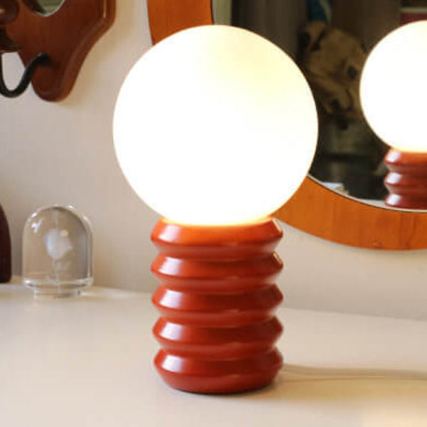 Decorative lamp with a red base and white bulb on a surface.