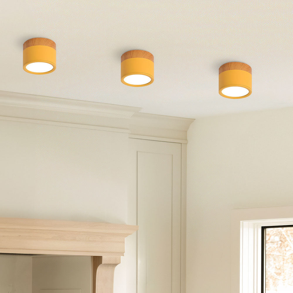 Three ceiling lights with yellow shades on a white ceiling.