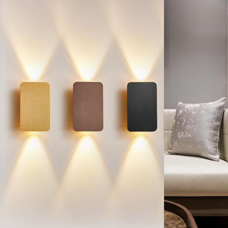 Three wall-mounted lights on a wall with a sofa and pillow in the background