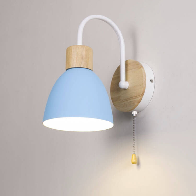 Wall-mounted lamp with blue shade and wooden base on a gray wall